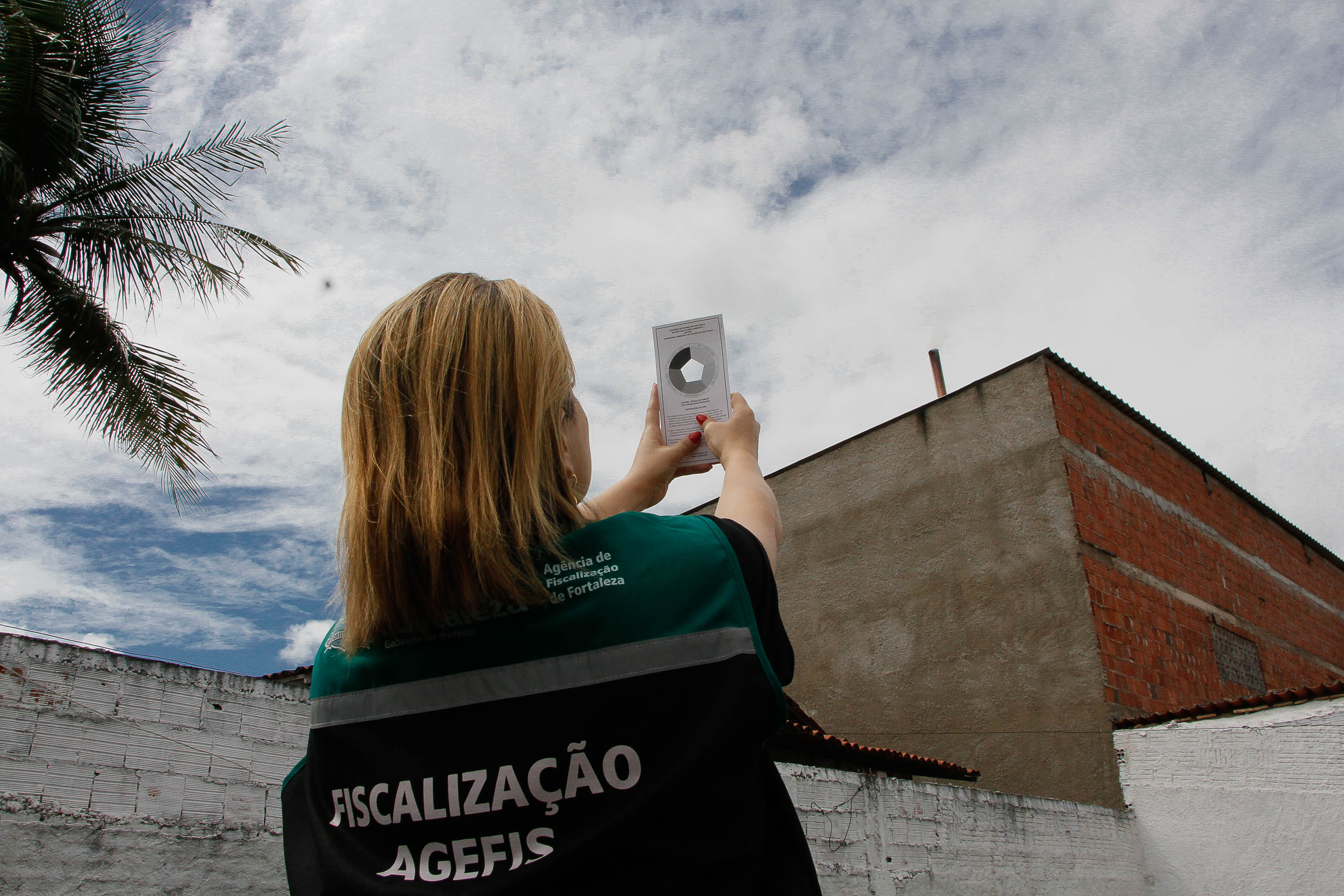 mulher aponta para uma chaminé que está emitindo fumaça